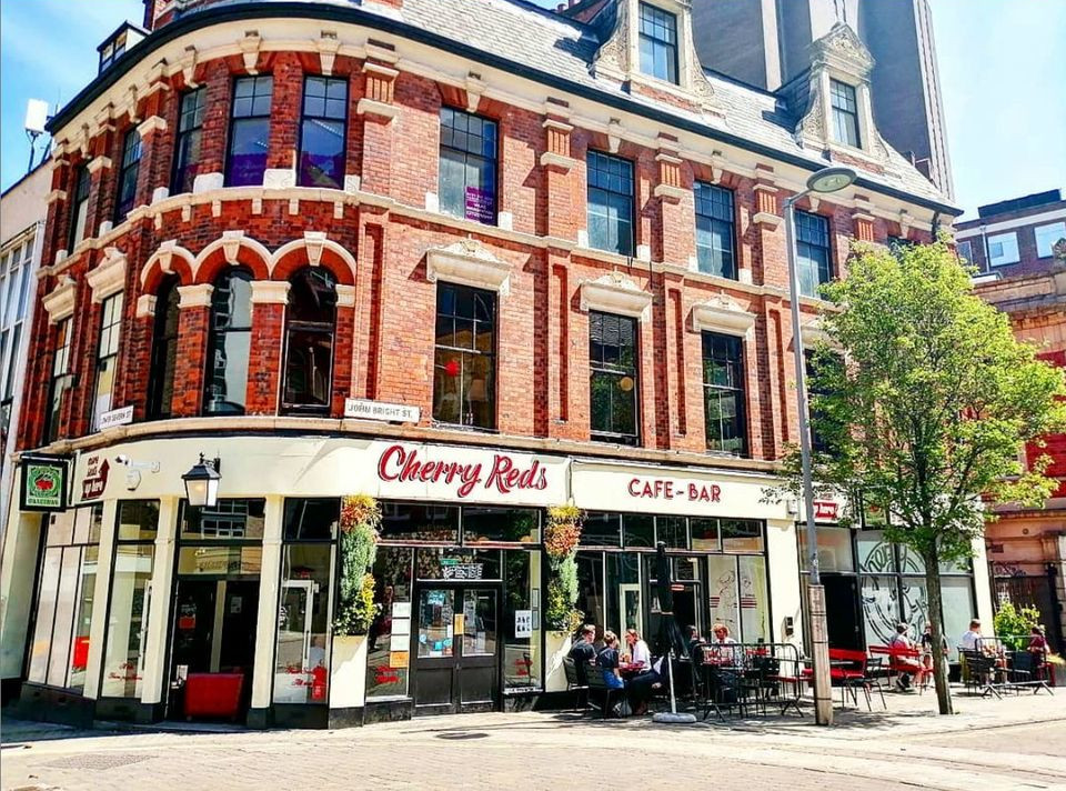 A three storey redbrick corner building with 'Cherry Reds cafe bar' written on the front
